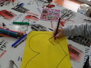 Criança a desenhar num coração amarelo.
