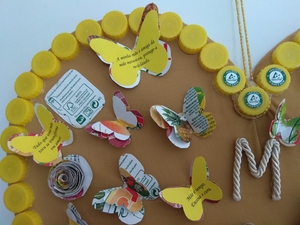 foto 2 identifica os símbolos exigidos e a forma como foram utilizadas as embalagens para decorar o coração com flores e borboletas. E ainda a aplicação das frases.