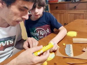 Encaregado de educação elaborando o coração amarelo com o filho (aluno)