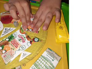 Recorte /colagem/enfeite de partes das embalagens dos sumos Compal no coração amarelo da Mãe, com destaque para o símbolo da Tetra Pak