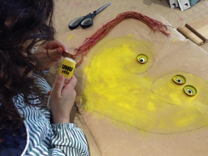 Materiais de desperdício para dar vida ao usado.
Com cordas que pintamos de laranja, amarelo e vermelho, fizemos os cabelos da mãe e da filha. Com caricas, fizemos os olhos.