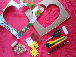 Preparação dos materiais para a construção do coração. 
Ilustra materiais utilizados na elaboração do coração, nomeadamente cartão aproveitado de uma caixa; embalagem Tetra Pak da Compal; rolhas de cortiça, bem como os moldes para o coração e as flores.