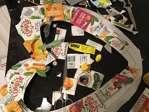 Recorte  dos símbolos Tetra Pak e FSC  bem como de elementos decorativos das embalagens Compal. Colagem  destes sobre o coração.