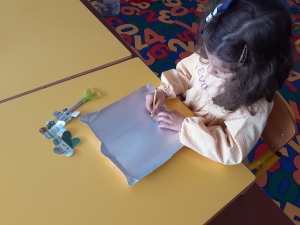 A criança a marcar com um lápis as flores na embalagem para depois recortar